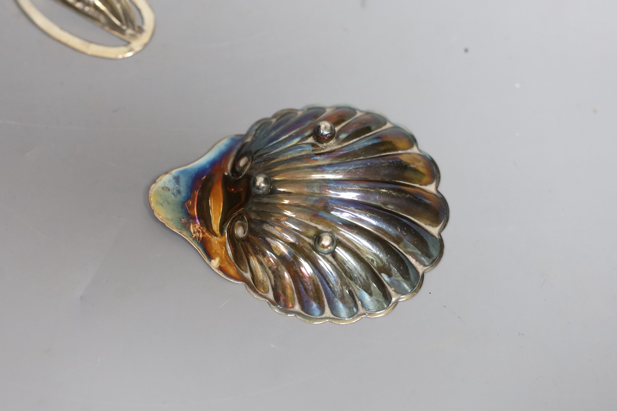 A pair of silver menu card holders, each decorated with a pheasant, Sampson Mordan & Co, Chester, 1907, width 59mm and a silver butter shell.